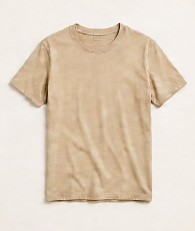 A flat-lay photograph of a beige cotton t-shirt on a cream studio backdrop